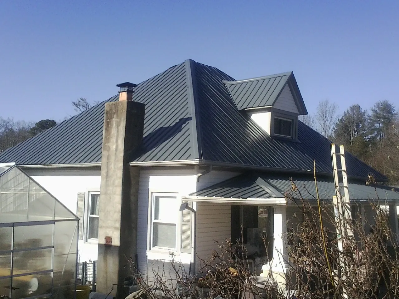 Dark blue standing seam metal roof on a white farmhouse with dormer — Slate & Tile Roof Repair by Roofing Brothers in Yonkers