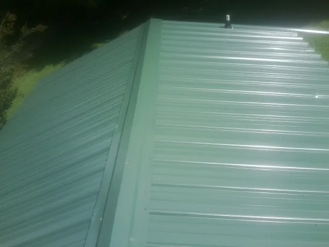 New green metal panels meeting at the ridge of a roof — Flat Roof Repair work by our crew in Yonkers