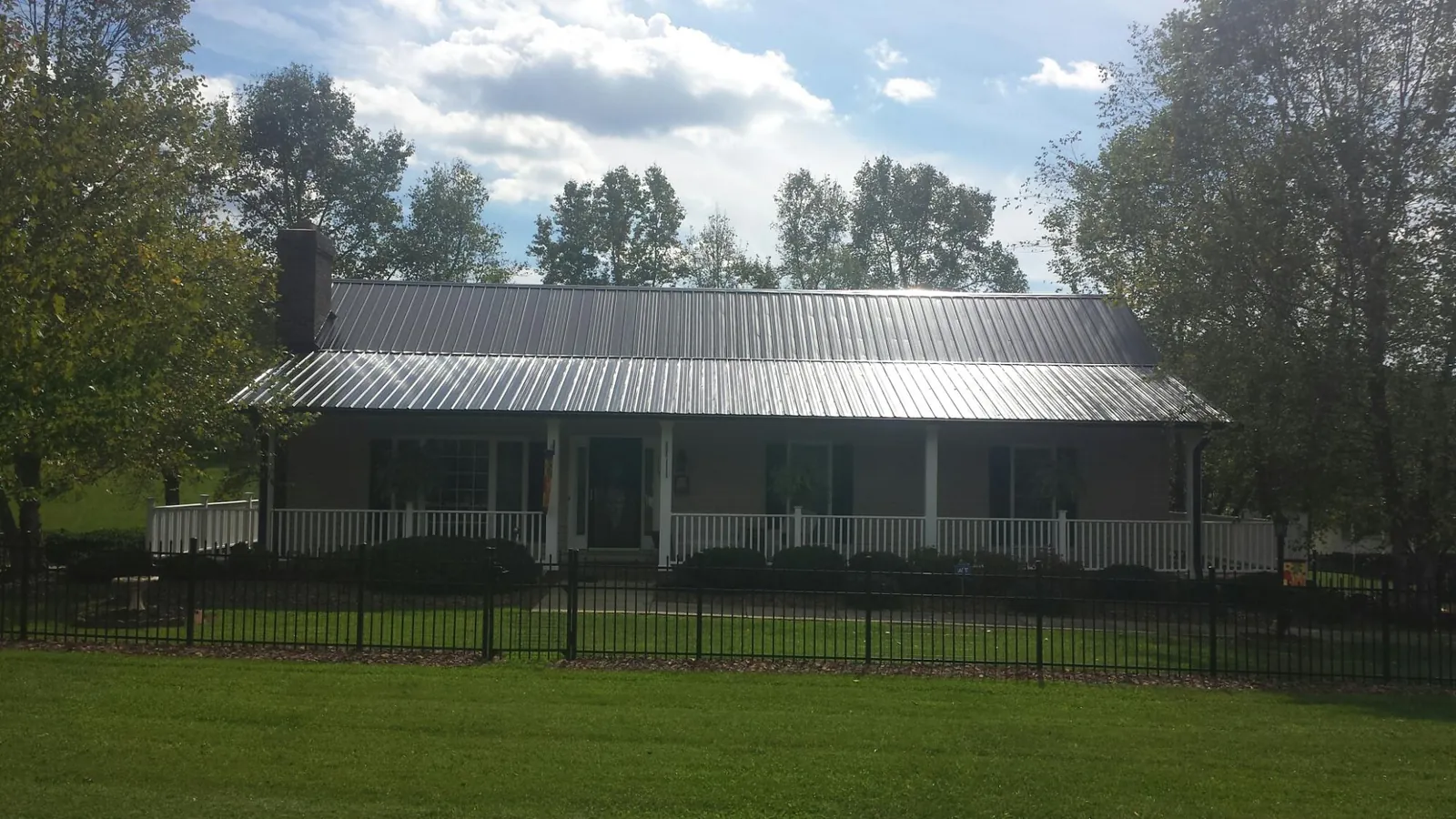 Gray metal roof on a brick ranch with a full width front porch in Yonkers