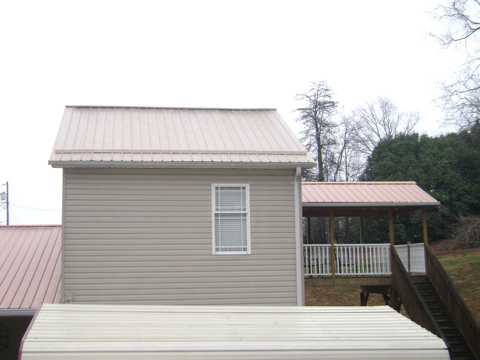 Tan metal roofs on a two story addition and attached porch, from a Roof Replacement job in Yonkers