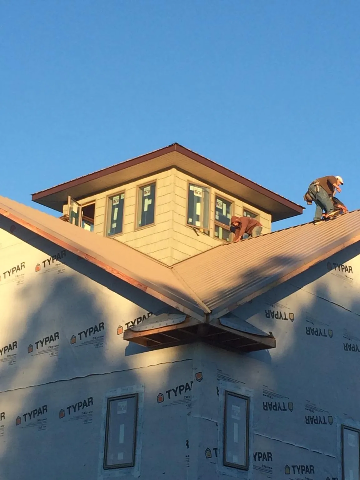 Roofers working around a rooftop cupola on a new metal roof at sunset — Roof Waterproofing in Yonkers by Roofing Brothers